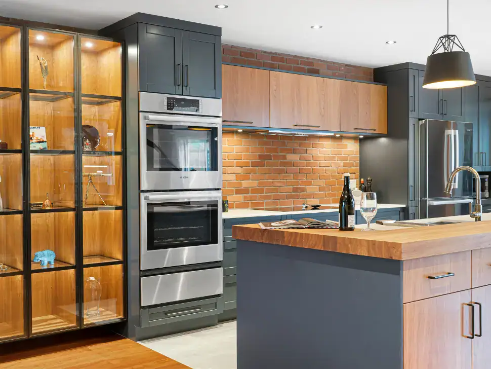 Style de cuisine industriel combinant armoires noir mat, surfaces en bois et éclairage suspendu dans un décor urbain